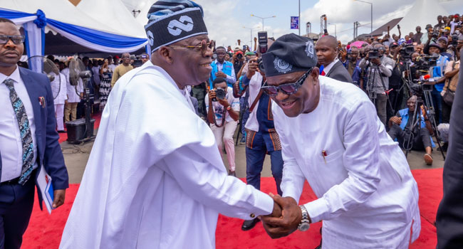 President Bola Tinubu and FCT Minister Nyesom Wike in a warm handshake during an event
